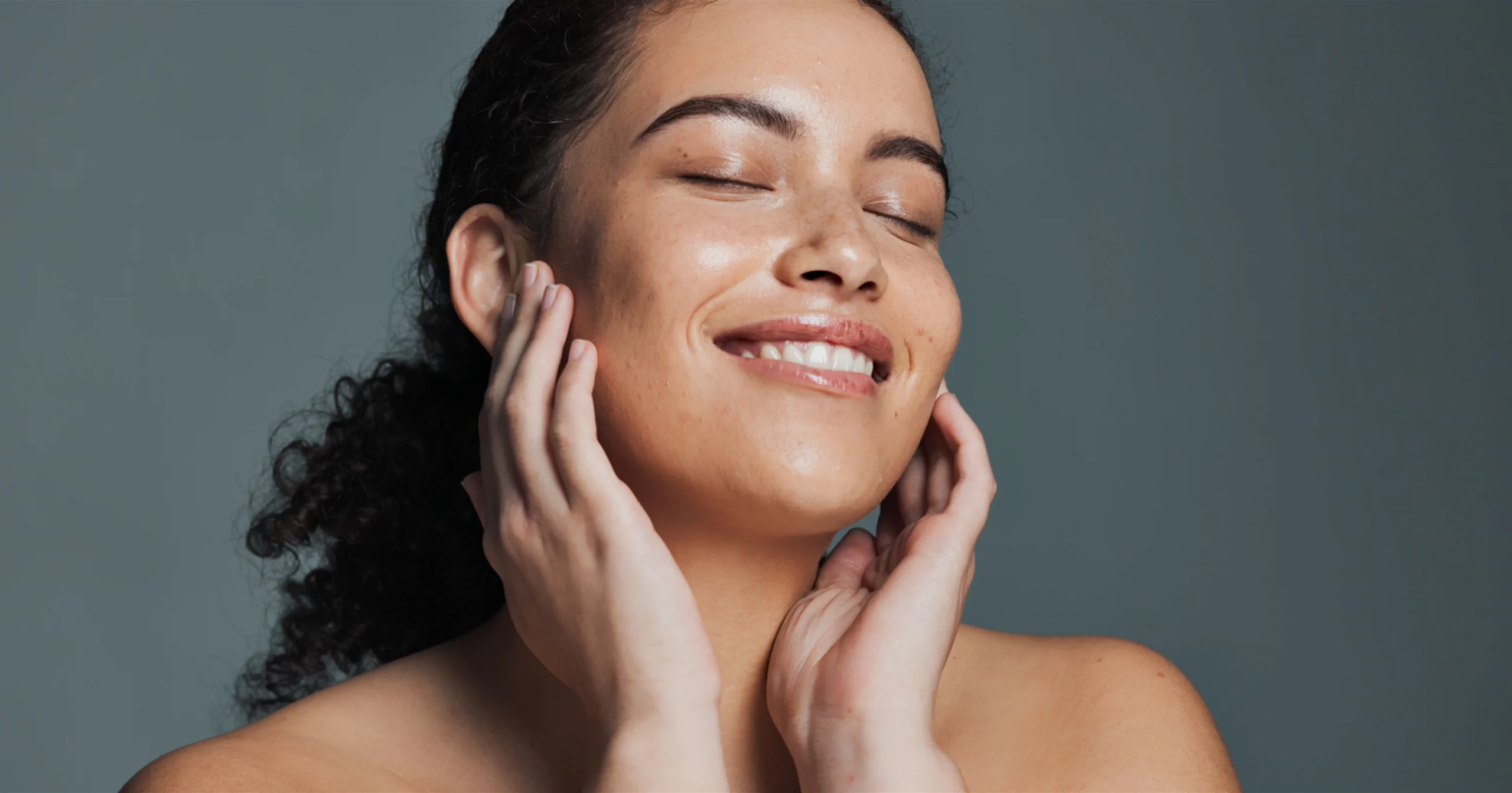 Smiling woman with glowing skin touching her face